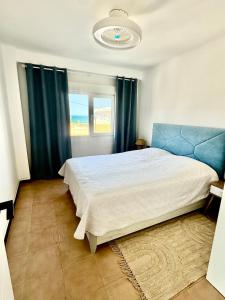 ein Schlafzimmer mit einem großen Bett und blauen Vorhängen in der Unterkunft The Cozy Coast in Piles