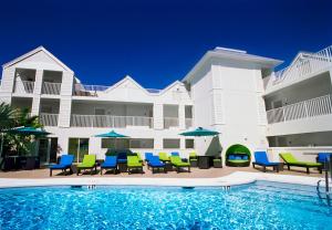 una piscina con sillas y sombrillas frente a un edificio en Silver Palms Inn en Cayo Hueso