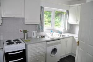 a white kitchen with a washing machine and a sink at Eaglesfield House Guest Apartment in Donaghey