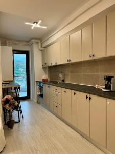 una cucina con mobili bianchi, un tavolo e una finestra di Studio Park Residence Apartment a Râmnicu Vâlcea