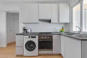 a white kitchen with a washing machine and a sink at La Brisa de Pilar in El Mojón