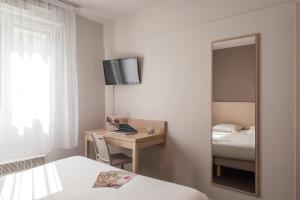 Habitación de hotel con cama y escritorio con espejo. en Appart'City Classic Lyon Part Dieu Garibaldi, en Lyon