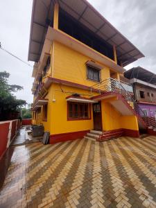 a yellow house with a tiled courtyard in front of it at Vista Valley Stay-Gokarna in Kumta