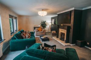 a living room with green couches and a fireplace at FAMILY FRIENDLY, HOT TUB, Fire Pit, Spacious & Modern in Fochabers