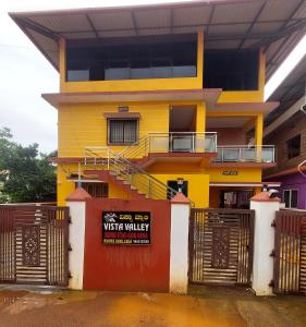 a yellow building with a gate in front of it at Vista Valley Stay-Gokarna in Kumta +5 photos