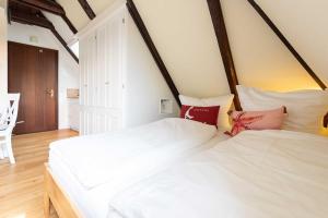 two white beds in a room with aamed ceilings at Sylter Wohlfühlnest, App 2 in Wenningstedt