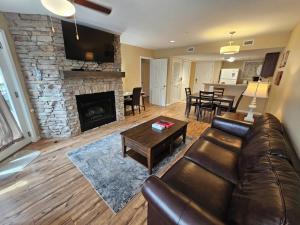 Una sala de estar con un sofá de cuero y una chimenea. en River's Edge, en Gatlinburg