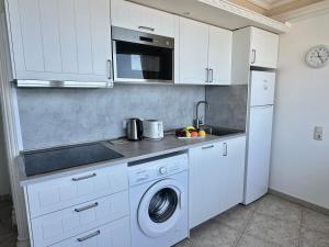 a kitchen with white cabinets and a washer and dryer at Direct at the beach - Arguineguin in Arguineguín