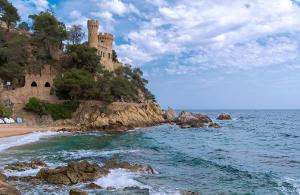 a castle on a cliff next to the ocean at Hostal Blanc Lloret in Lloret de Mar