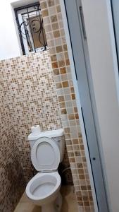 a bathroom with a toilet and a tile wall at Dee's Super Luxury Studio Apartment Bamburi in Mombasa