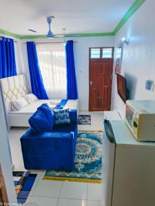a living room with a blue couch and a bed at Dee's Super Luxury Studio Apartment Bamburi in Mombasa