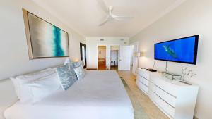 ein weißes Schlafzimmer mit einem großen weißen Bett und einem Flachbild-TV in der Unterkunft South Bay Beach Club #31- 3 Bedroom 2 Bathroom Unit in George Town