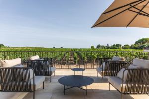 a patio with chairs and a table and an umbrella at La Villa des Vignes in Saint-Émilion