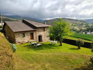 a stone house with a table and chairs in the yard at La casa de atrás in Arancedo