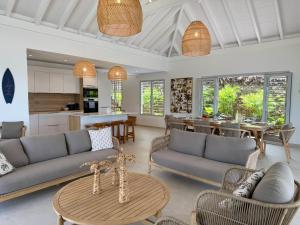 Una sala de estar con sofás y una mesa y una cocina. en EAST KEYS - East Blue Villas, en Le Vauclin