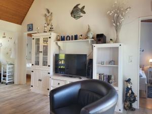 布特亚丁根Ferienhaus Klein的客厅里有一台电视和一把黑色皮椅。