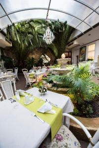 a restaurant with white tables and chairs and plants at Golden Royal Boutique Hotel & Spa in Košice