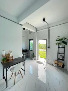 a white living room with a table and chairs at บ้านK village in Ban Rawoeng