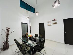 a dining room with a glass table and black chairs at Ethereal Ipoh Homestay in Ipoh