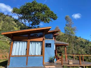 a small house with white curtains on a deck at Chalé Alecrim in Córrego do Bom Jesus