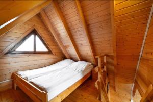 a bed in a wooden cabin with a window at Domki Port Jastarnia in Jastarnia