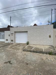 ein weißes Backsteingebäude mit zwei Garagentüren in der Unterkunft Temporada CG - Casa altíssimo padrão no Cruzeiro in Campina Grande