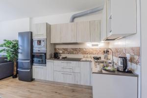 a kitchen with white cabinets and a black refrigerator at Prime Living Milano Merlata - Balcony Apartment in Milan