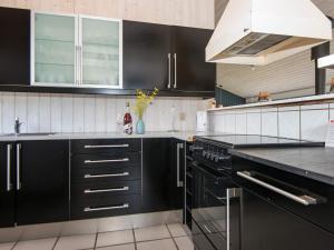 Sønderbyにある10 person holiday home in Juelsminde-By Traumの黒いキャビネットと花瓶付きのキッチン +34枚の写真