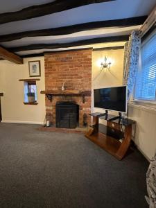 a living room with a fireplace and a flat screen tv at Rosemary cottage in Mountnessing +9 photos
