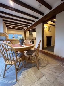 a kitchen and dining room with a wooden table and chairs at Rosemary cottage in Mountnessing