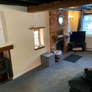 a living room with a fireplace and a television at Rosemary cottage in Mountnessing
