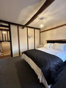 a bedroom with a large bed with a black blanket at Rosemary cottage in Mountnessing