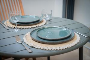 a table with two plates and wine glasses on it at T2 cosy - Ti nid vert in La Possession