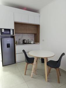 eine Küche mit einem Tisch, 2 Stühlen und einem Kühlschrank in der Unterkunft Departamentos San Martin in San Pedro
