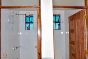 a bathroom with a white tiled shower with a mirror at Eldoret 3bedroom Apartment in Eldoret