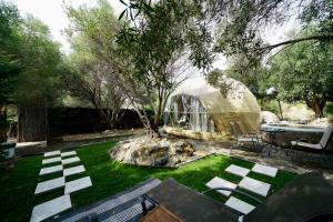 a garden with a dome greenhouse and a tree at Olive Domes in Nea Moudania
