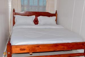 a wooden bed with white sheets and pillows at Eldoret 3bedroom Apartment in Eldoret