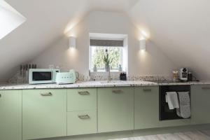 a kitchen with white cabinets and a window at Luxury One Bed Annnex on Rodborough Common in Woodchester +16 photos