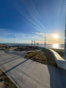 an empty road next to the ocean with the sun setting at Roma apartamento 2 frente al mar in Mar del Plata
