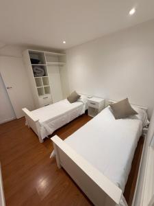 two beds in a room with white walls and wood floors at Roma apartamento 2 frente al mar in Mar del Plata +10 photos