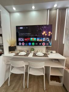 バコロドにあるPatrini Solace 619B - Bacolod Condoの白い机と椅子、そして大きなスクリーン +3枚の写真