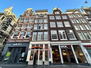 a tall building on a city street with stores at Hotel Damrak Inn in Amsterdam