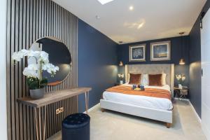 チェルトナムにあるLuxurious 1 Bed Detached Home with Gated Parkingのベッドルーム1室(青い壁のベッド1台、鏡付)