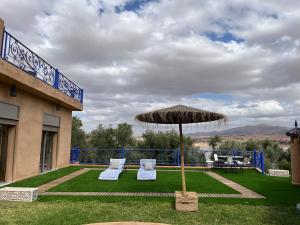 a patio with an umbrella and two chairs and a table at Dar NFis Suites et chambres de luxe dans un havre de paix vue paradisiaque au bord du lac in Lalla Takerkoust