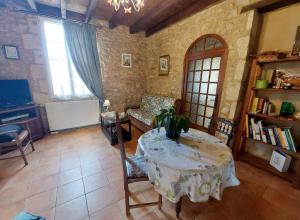 Zimmer mit einem Tisch, einem Sofa und einem TV in der Unterkunft Maison des Hortensias à 500 m des bords de rivière in Limeuil
