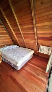 a bed in a room with a wooden floor at Refúgio da natureza in São Francisco do Sul