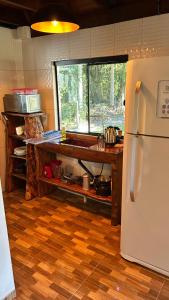a kitchen with a white refrigerator and a wooden floor at Refúgio da natureza in São Francisco do Sul