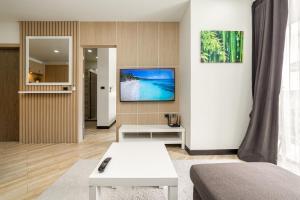 a living room with a tv on a wall at Calypso Garden Residences by Beringela in Phuket Town