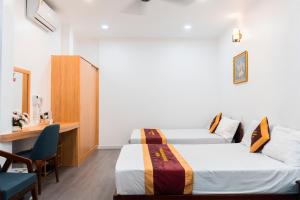 a hotel room with two beds and a desk at Belvilla Near Quang Trung Exhibition Center District 12 Formerly Southern Star Hotel in Ho Chi Minh City