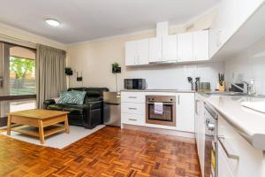 una cucina con mobili bianchi e un soggiorno di Compact and Convenient Unit - Hosted by Canstay a Canberra